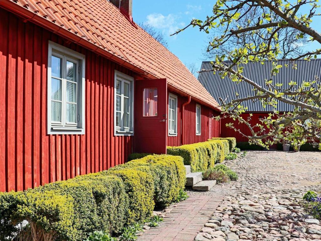 um edifício vermelho com uma fileira de arbustos à sua frente em Holiday home BÅSTAD em Båstad