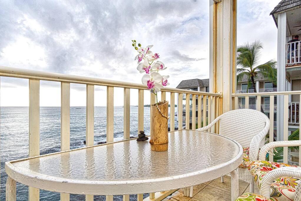 a table and chairs on a balcony with the ocean at Beautiful Oceanfront Condo! - Hale Kona Kai 303 in Kailua-Kona