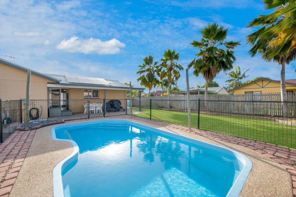 a swimming pool in a yard with a fence and palm trees at Vibrant, Lovely 3BR Family Home in North Ward