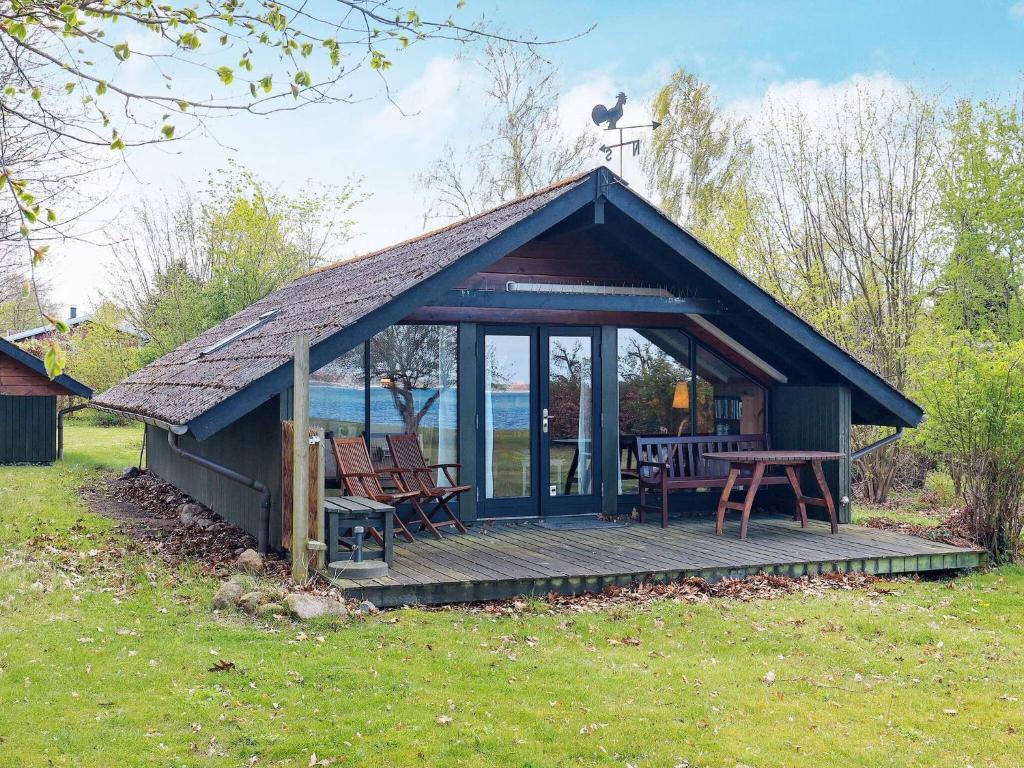 a cabin with a deck and a table and chairs at Holiday home Stubbekøbing III in Stubbekøbing