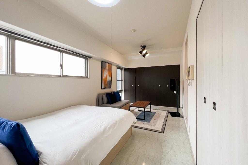 a bedroom with a bed and a chair and a table at Trioni EBISU in Osaka