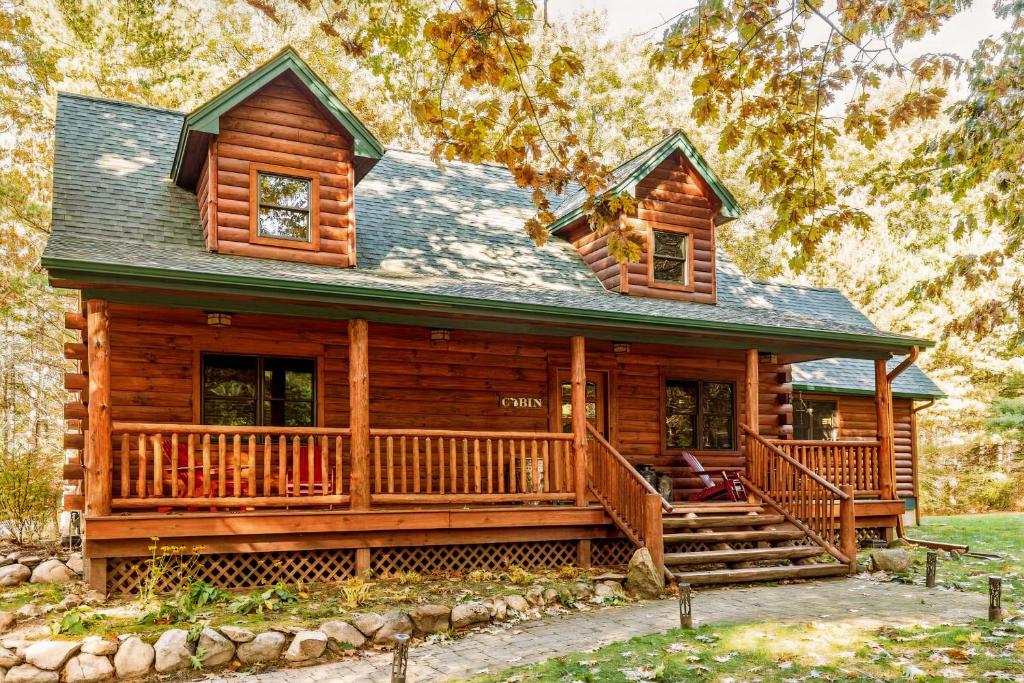 a log cabin with a large porch and a green roof at Torch Lake Cabin In The Woods THE HEART OF TORCH in Bellaire