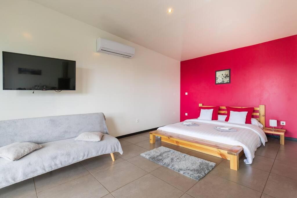 a room with two beds and a red wall at Le Panorama in Cilaos