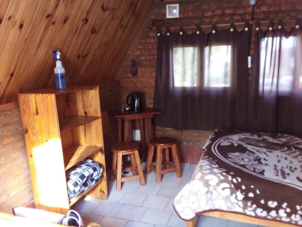 ein Schlafzimmer mit einem Bett und zwei Hockern in einem Zimmer in der Unterkunft El Cristal in Puerto Pirámides