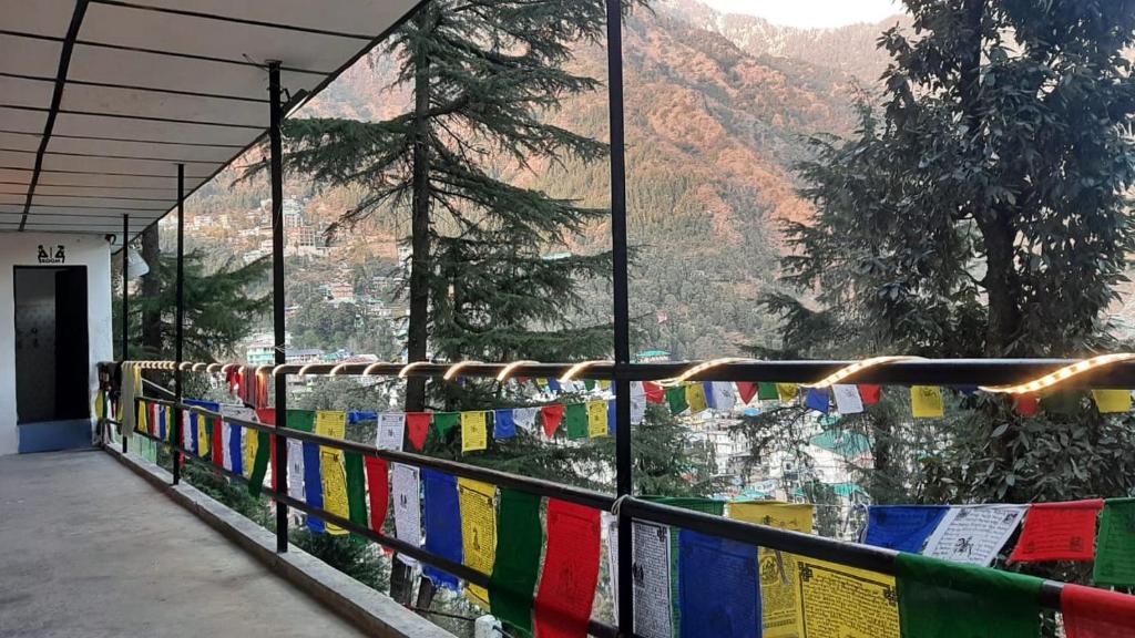 un balcón con banderas de oración y vistas a la montaña en Thrillomania Mcleodganj en Dharamshala