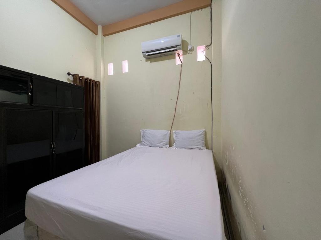niewielka sypialnia z białym łóżkiem i grzejnikiem w obiekcie SPOT ON 92547 Wisma Dg Tata w mieście Makasar