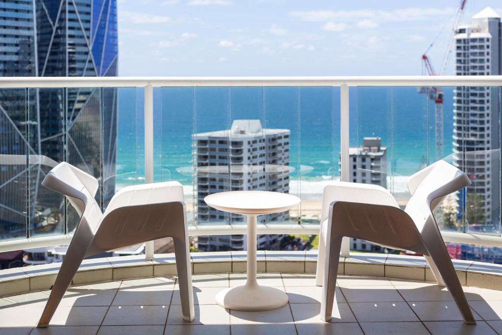 Luxury Ocean View Studio Apartments في غولد كوست: طاولة وكراسي على شرفة مطلة على المحيط