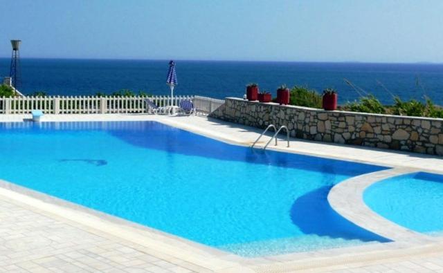 a large swimming pool with the ocean in the background at Nicolas Apartments in Ierapetra