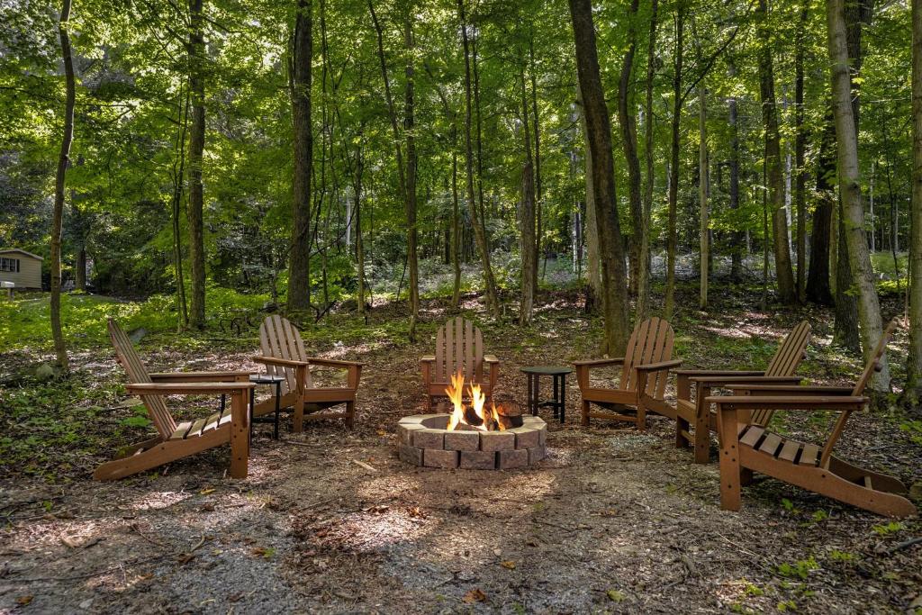 a group of chairs around a fire pit in the woods at Modern Cabin w Hot Tub Fire Pit WiFi in Berkeley Springs