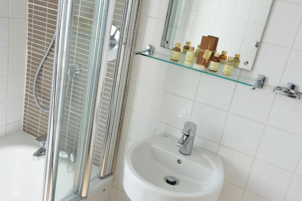 a white bathroom with a shower and a sink at The White Lion Hotel in Aldeburgh