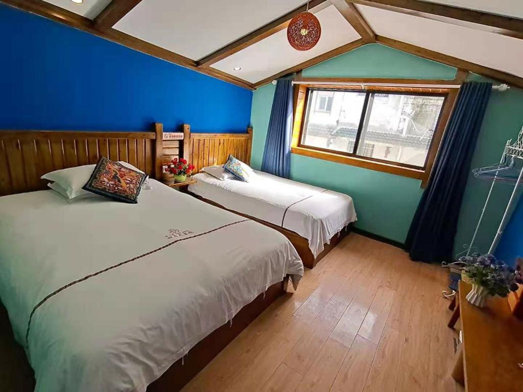 two beds in a room with blue walls and a window at Zhangjiajie April Hostel in Zhangjiajie
