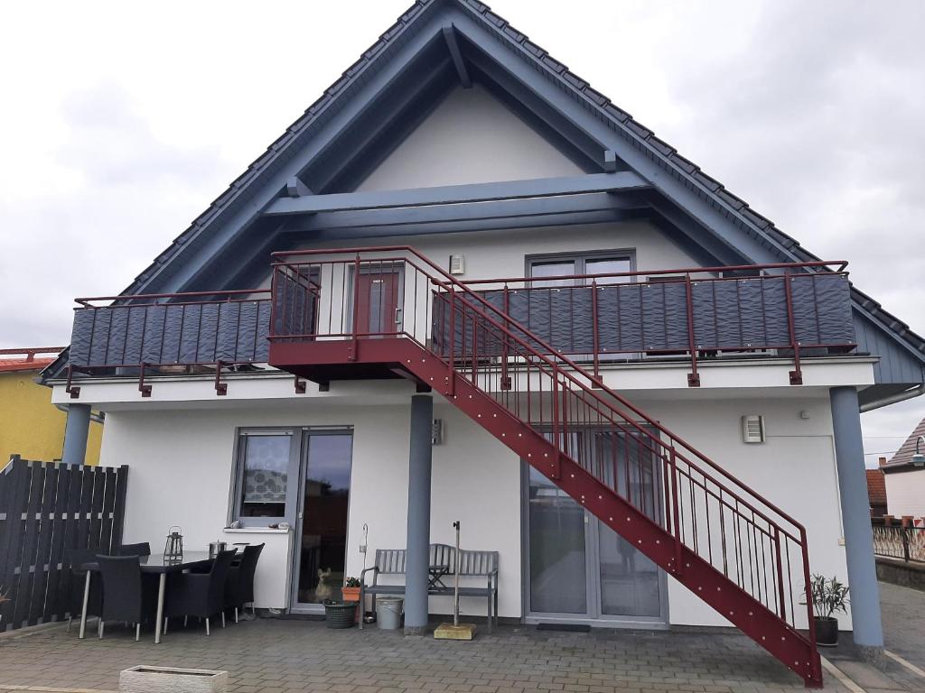 Una casa blanca con una escalera roja. en Ferienwohnung Richter en Luckau