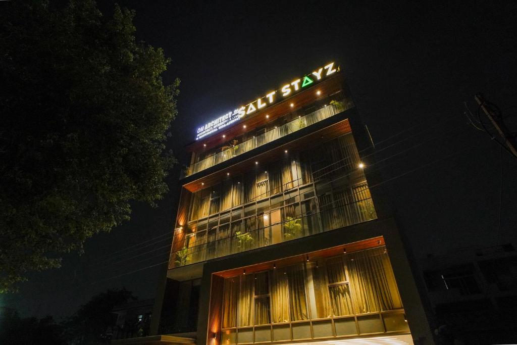 um edifício com um sinal em cima dele à noite em Saltstayz Grand Sky - Unitech Cyber Park em Gurgaon