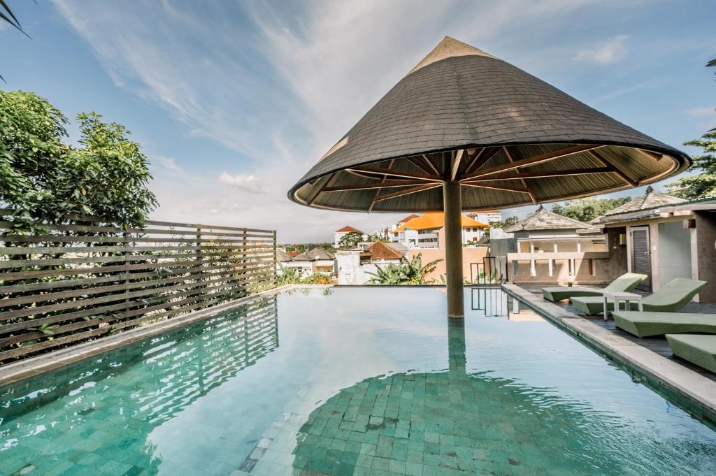 a swimming pool with a large umbrella and chairs at Abisha Villa Jimbaran in Jimbaran