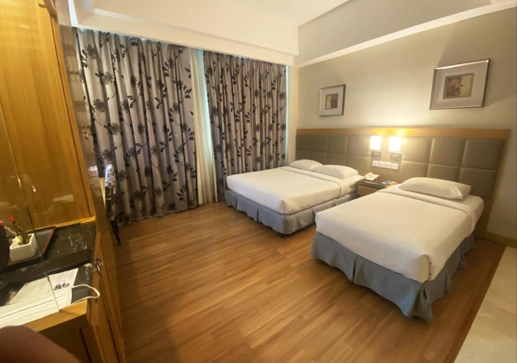a hotel room with two beds and a bathroom at Crown Garden Hotel in Kota Bharu