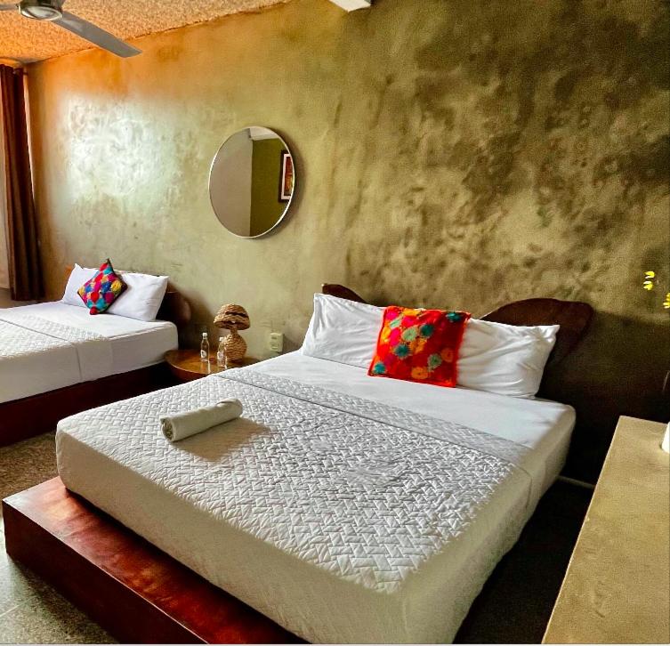 1 dormitorio con 2 camas y espejo en La Zona Hostel, en San Salvador