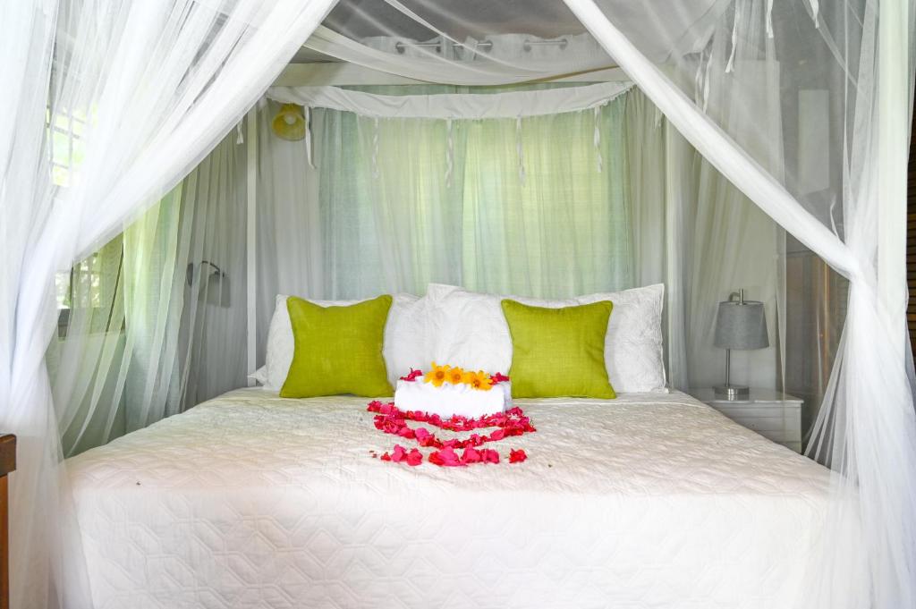 Una cama blanca con un dosel blanco con flores. en The Cottages - Unit 1 en Soufrière