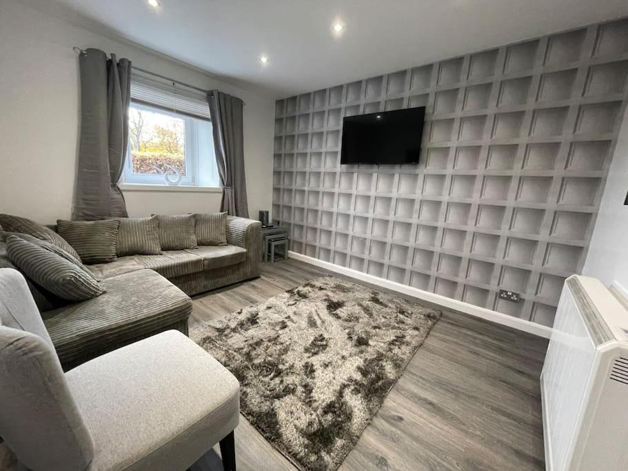 a living room with a couch and a flat screen tv at Lovely City Home in Edinburgh