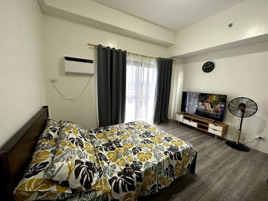 a bedroom with a bed and a flat screen tv at Minimalist studio unit in Davao City