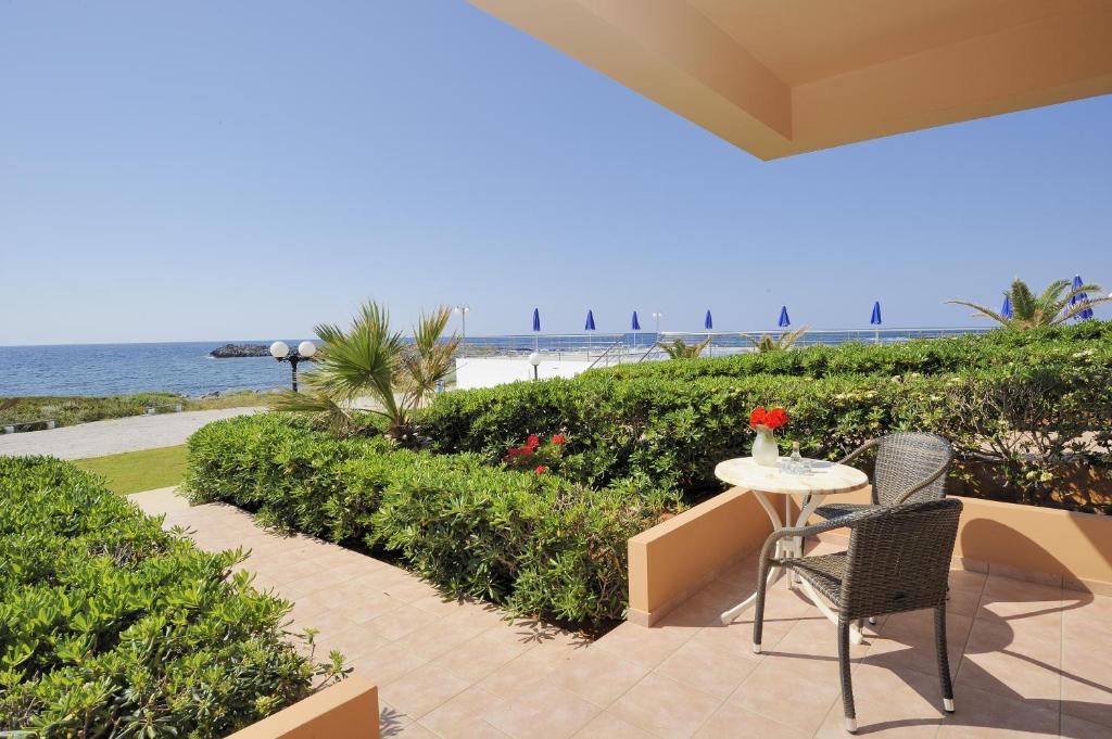 a patio with a table and chairs and the beach at Nanakis Beach Apartments in Stavros