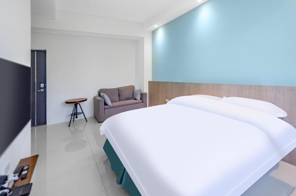 1 dormitorio con 1 cama blanca y 1 silla en 春雨漫居 Spring Rain Hostel, en Meishan