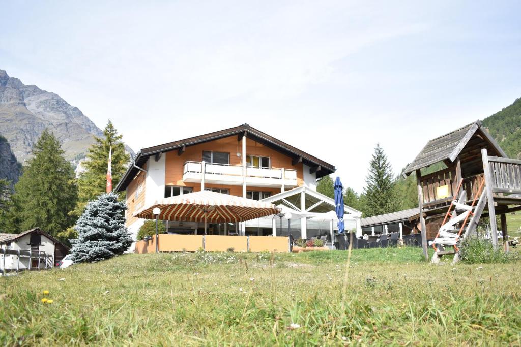 a large house in a field next to a mountain at Restaurant & Hostel Hole in One in Randa