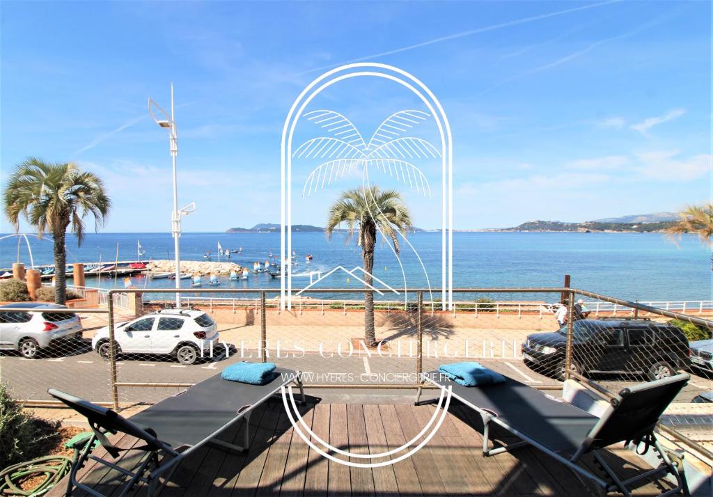 een uitzicht op een strand met palmbomen en de oceaan bij Villa Antoine Appartement RDJ Vue mer CLiM Wifi parking plage 50m La Garonne in Le Pradet