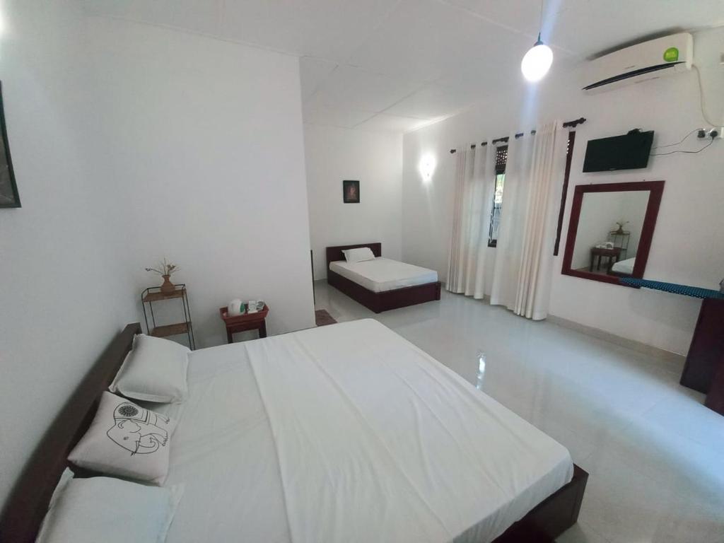 a white bedroom with a large bed and a couch at S & D Resort in Anuradhapura