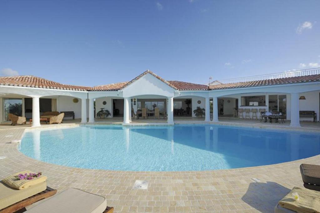 a large swimming pool in front of a house at Spacious villa with sea view in Saint Martin + private pool. in Les Terres Basses