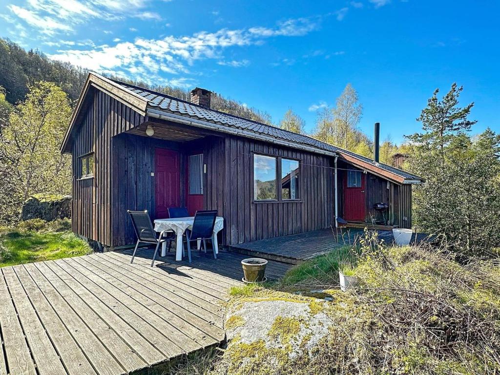 HelleにあるTwo-Bedroom Holiday home in Farsund 1の小さなキャビン(デッキにテーブルと椅子付)