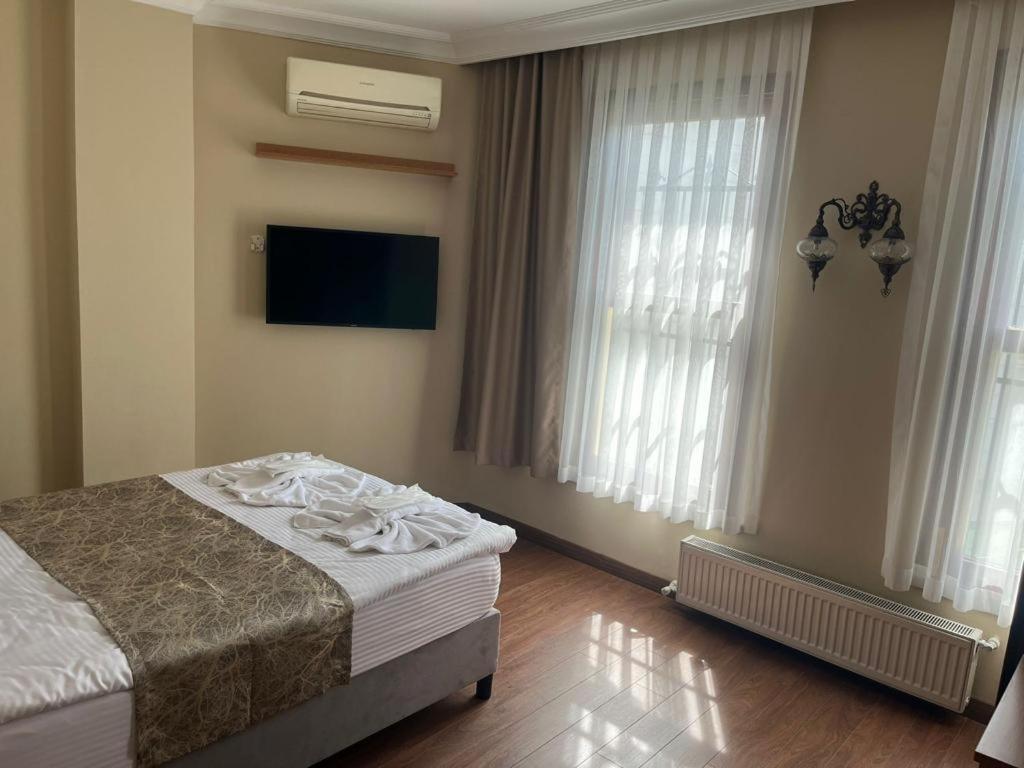 a bedroom with a bed and a tv and windows at Ottoman Elegance Hotel in Istanbul