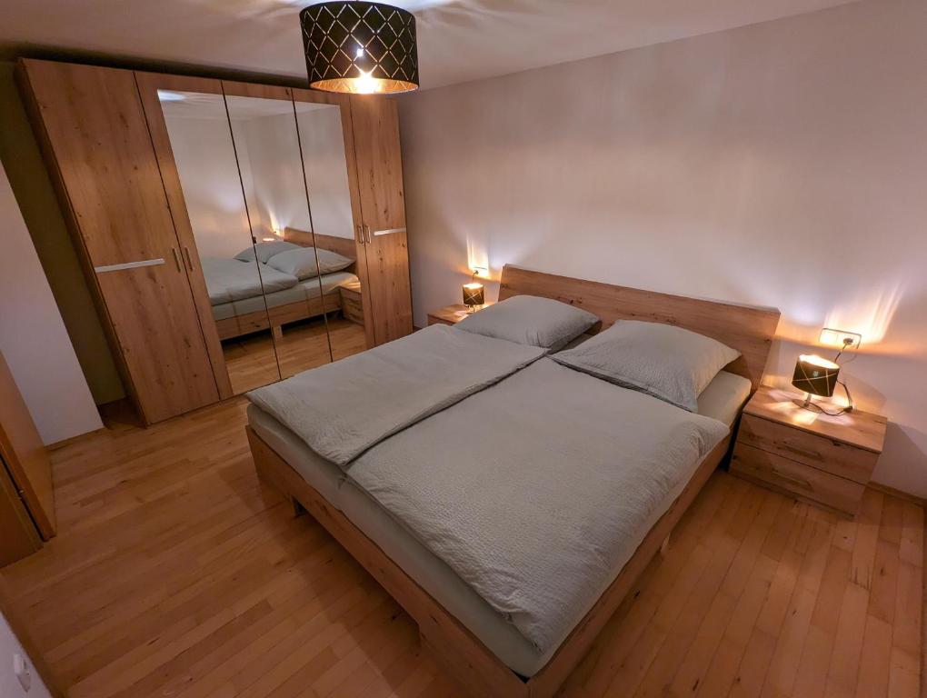 ein Schlafzimmer mit einem großen Bett und einem Spiegel in der Unterkunft Ferienwohnung Apimundi in Lauterach