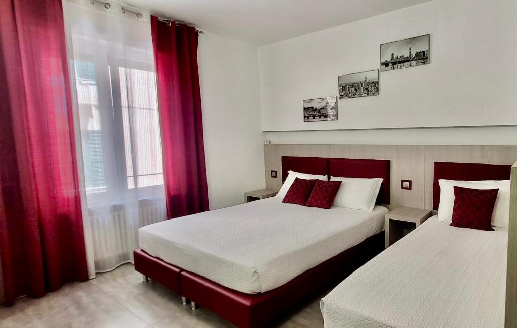 a bedroom with two beds with red curtains and a window at Eden Rooms in La Spezia