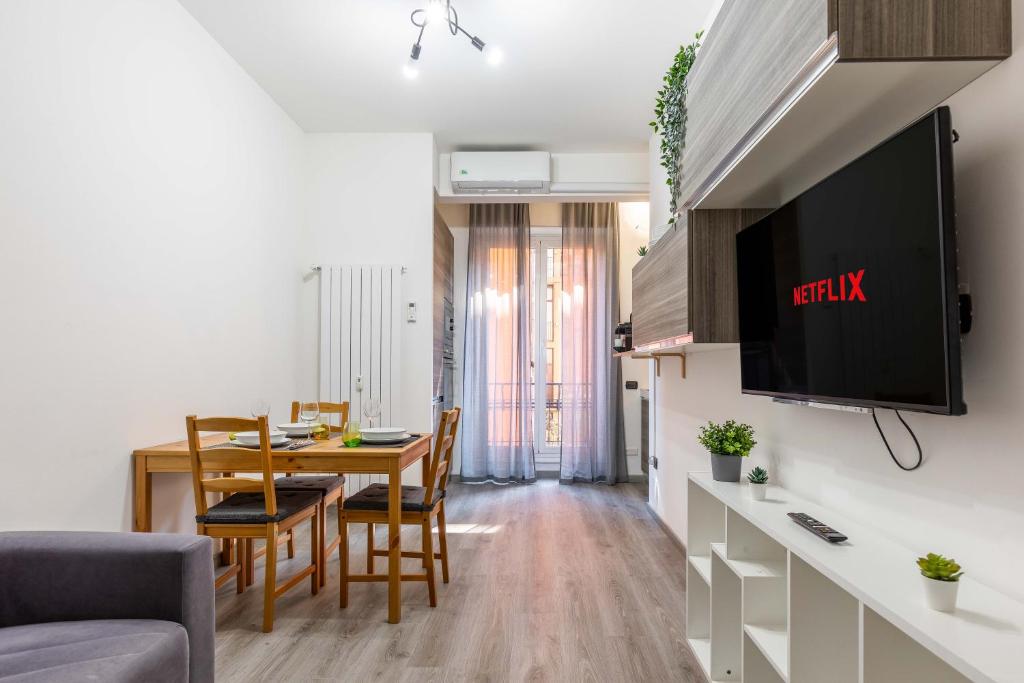 een woonkamer met een eettafel en een tv bij Central Station & Duomo - Shopping District Apartment in Milaan