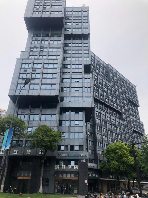 um edifício alto com pessoas à frente dele em He&Her Youth Hostel em Hangzhou