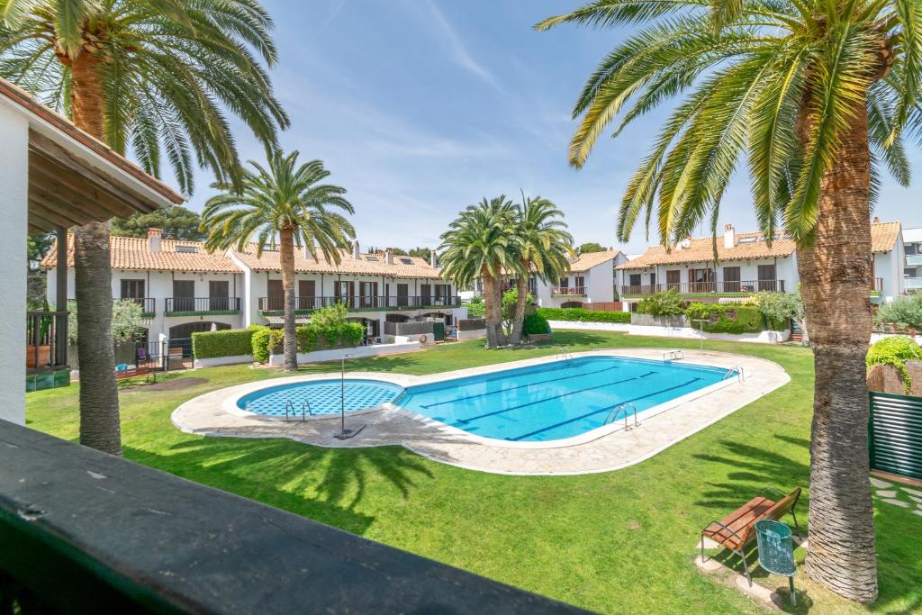 an image of a swimming pool in a yard with palm trees at Paola: Preciosa casa pareada con piscina in Sitges
