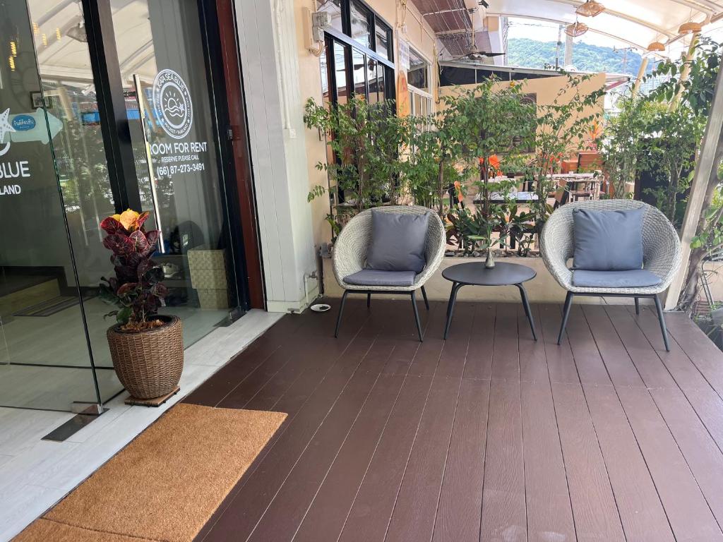 two chairs and a table in front of a building at Kata Sea Blue in Kata Beach