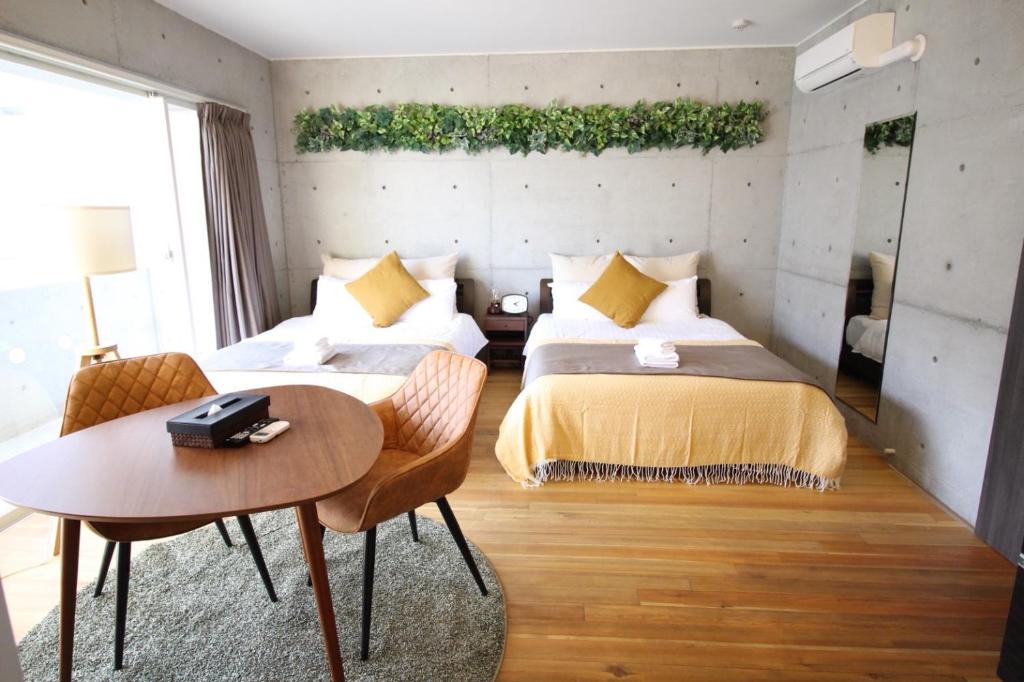 2 Betten in einem Zimmer mit Tisch und Stühlen in der Unterkunft TAKETO STAY Osakajo in Osaka
