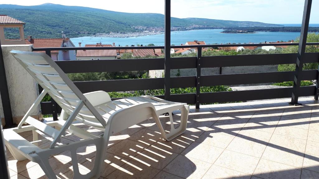 a white chair sitting on a balcony with a view of the water at Apartment Slavica in Kornić