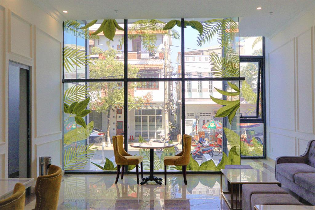 a room with a table and chairs and a large window at ATP Galaxy Hotel & Apartment Danang in Da Nang