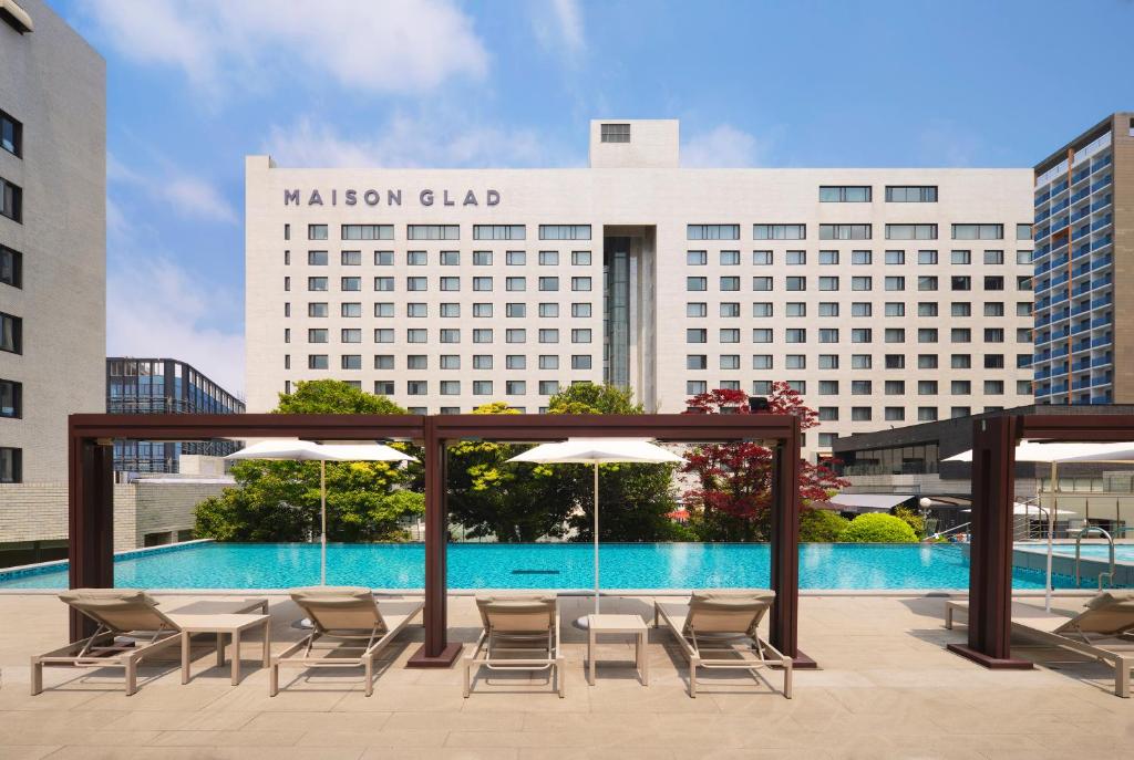 a patio with chairs and umbrellas in front of a hotel at Maison Glad Jeju in Jeju