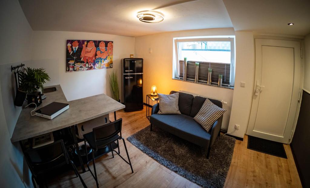 a living room with a blue couch and a desk at Gemütliche 2-Zimmer Souterrain Wohnung in Düsseldorf