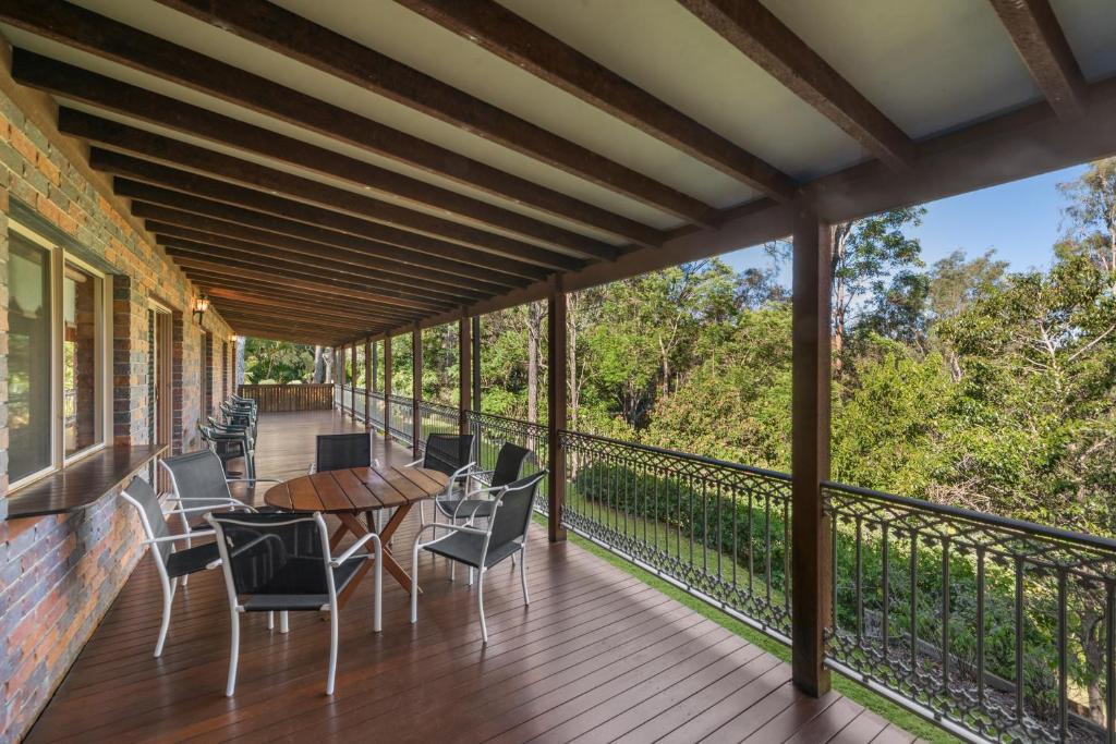 a deck with chairs and tables on a balcony at Coucals Cottage in Mount Crosby
