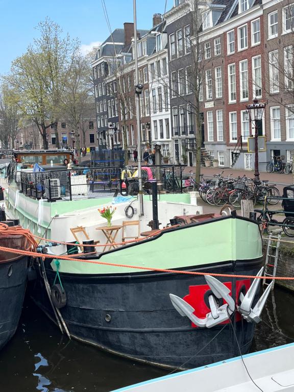 een boot is aangemeerd in een kanaal met gebouwen bij Skinny Bridge Houseboat Amstel View Amsterdam in Amsterdam