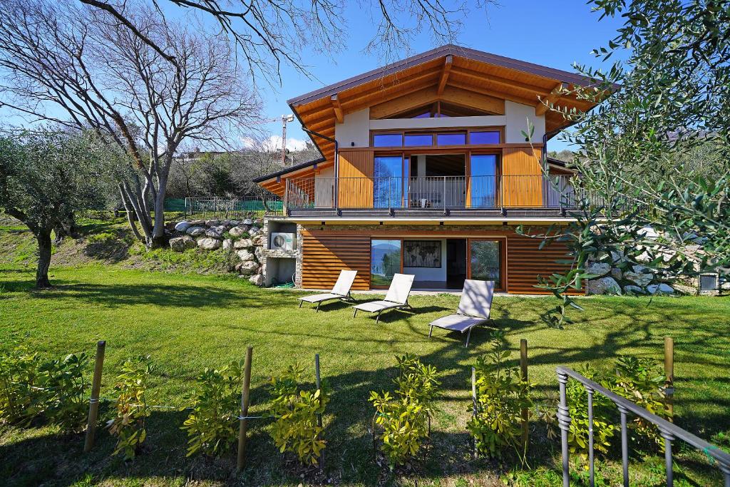 une maison sur une colline avec une cour avec des chaises dans l'établissement Ville in uliveto vista lago - VILLA LECCINO, à Pulciano