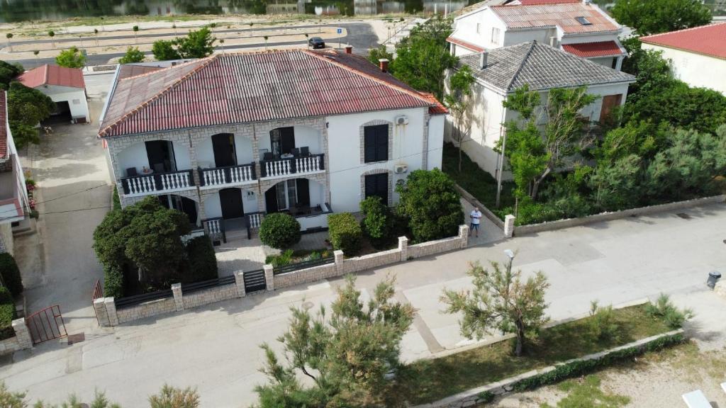 uma vista aérea de uma casa branca com um telhado vermelho em Rooms & Apartments Kaurloto em Pag