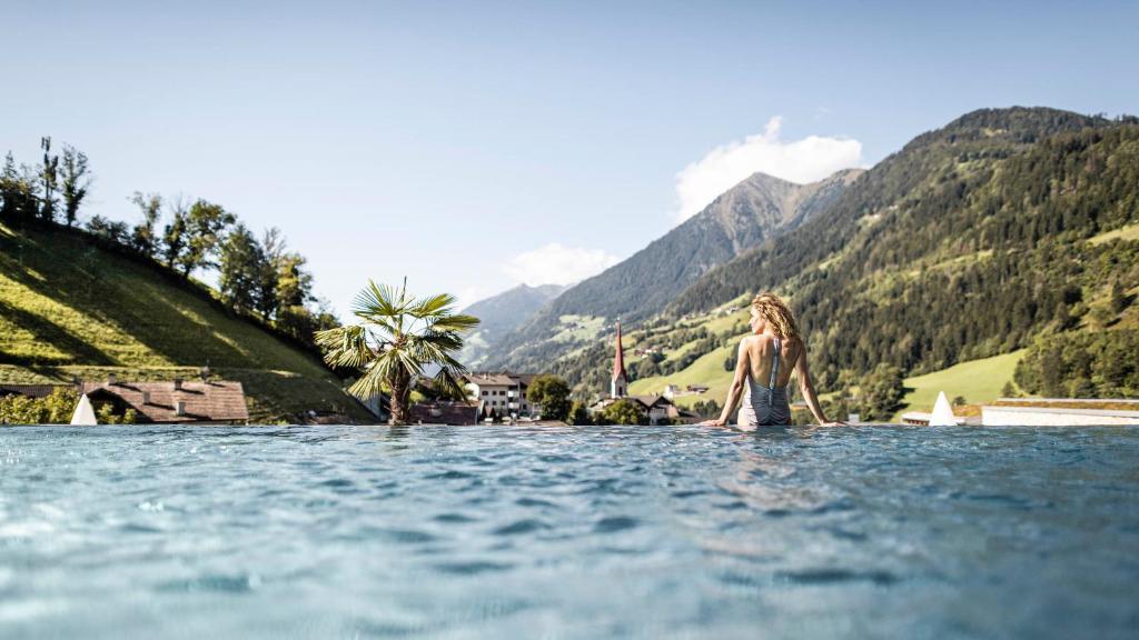a woman standing in the water in the mountains at Stroblhof Active Family Spa Resort in San Leonardo in Passiria