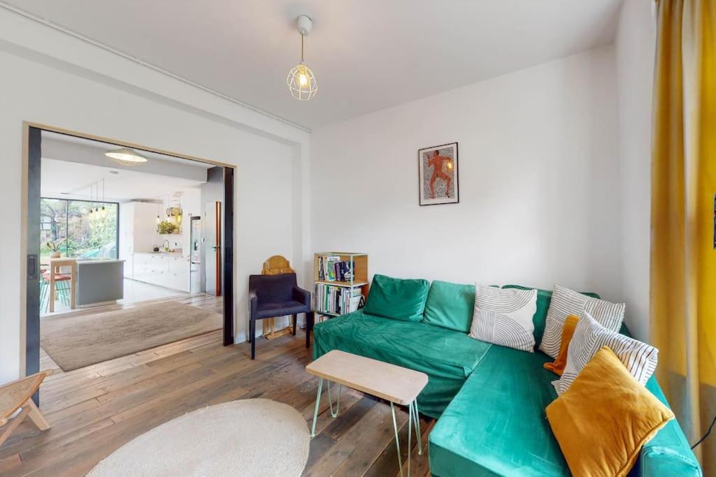 un soggiorno con divano verde e tavolo di Enchanting 3 bedroom house with garden in Leyton a Londra