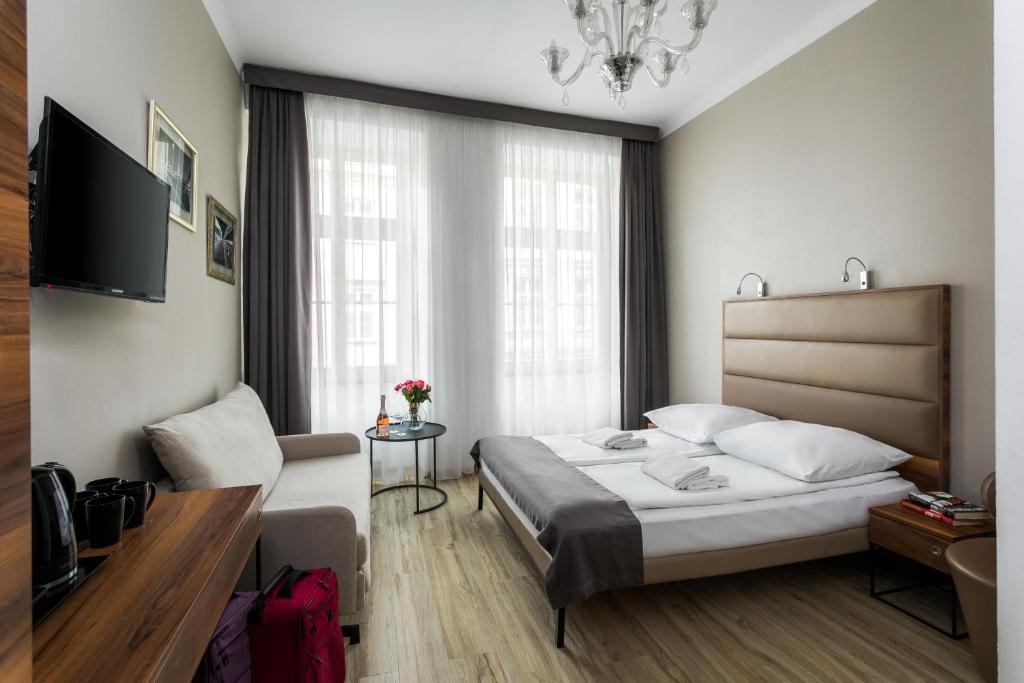 - une chambre avec un lit, un canapé et une télévision dans l'établissement G12 Aparthotel, à Cracovie