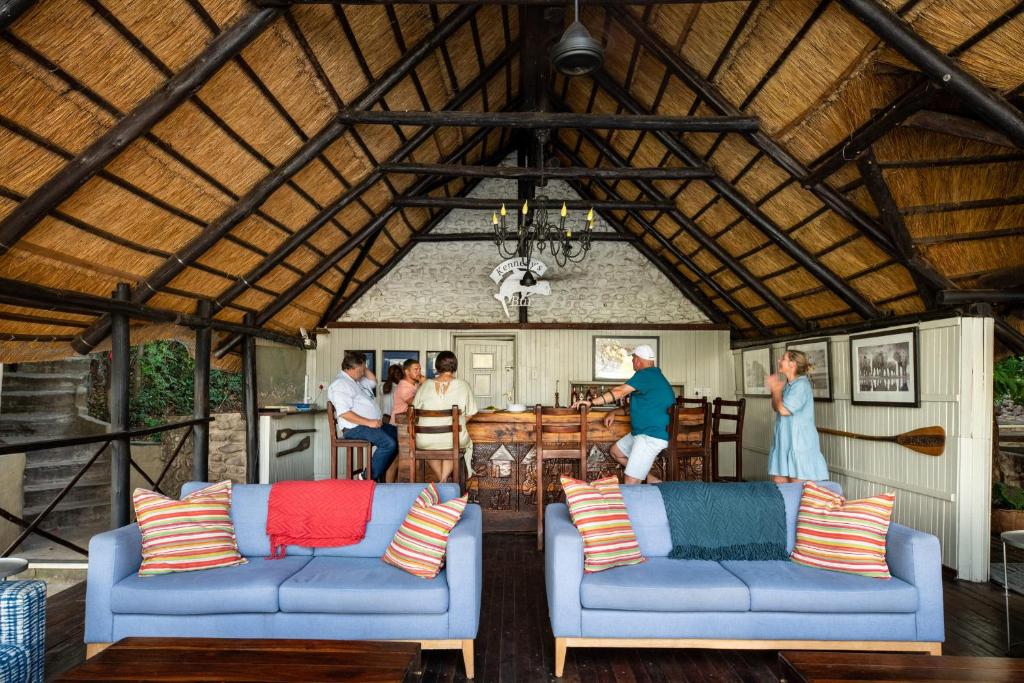 a living room with two blue couches and a group of people at Ichingo Chobe River Lodge by Mantis in Punga
